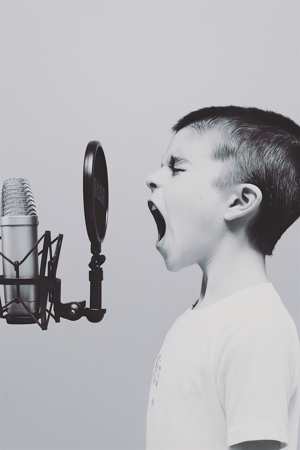Young voice talent recording a voice over demo on a studio microphone